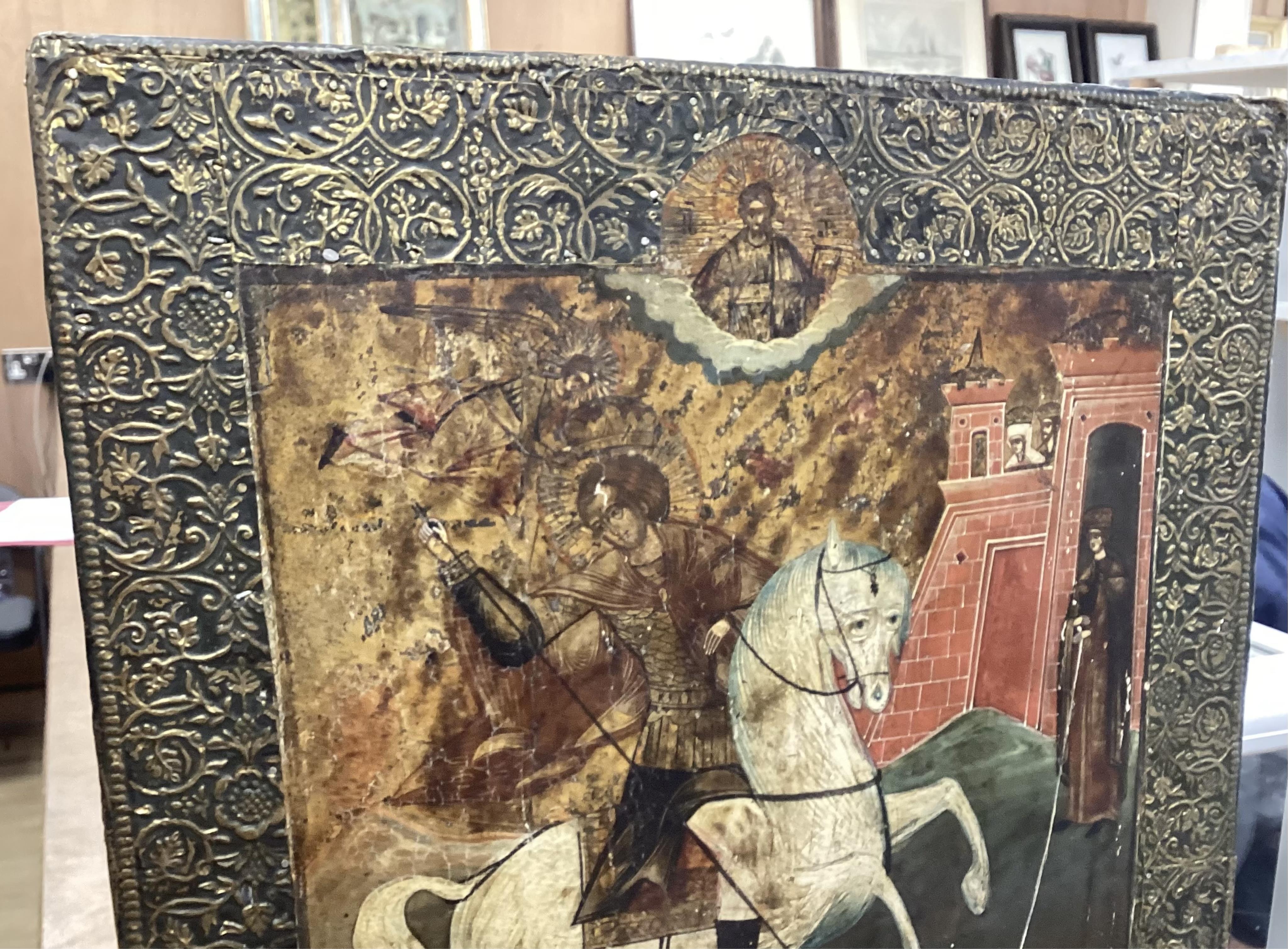 19th century Russian school, Icon, St George and The Dragon with Christ in Majesty above, applied stamped brass border, 45 x 37cm